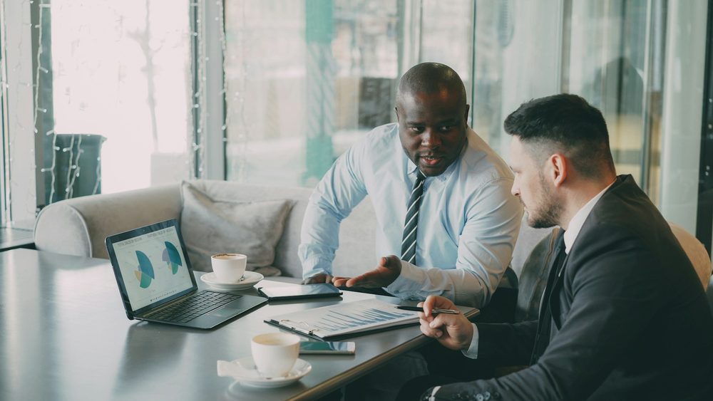 Two analysts reviewing charts on a laptop